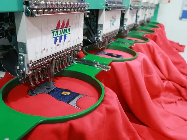 Máquinas de bordado industrial marcando camisetas rojas