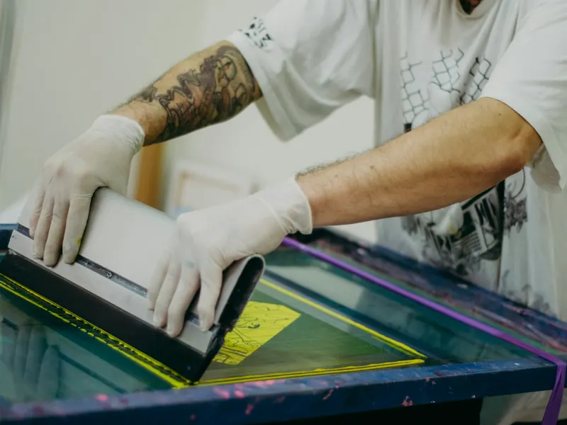 Operario pasando la racleta sobre una pantalla de serigrafía